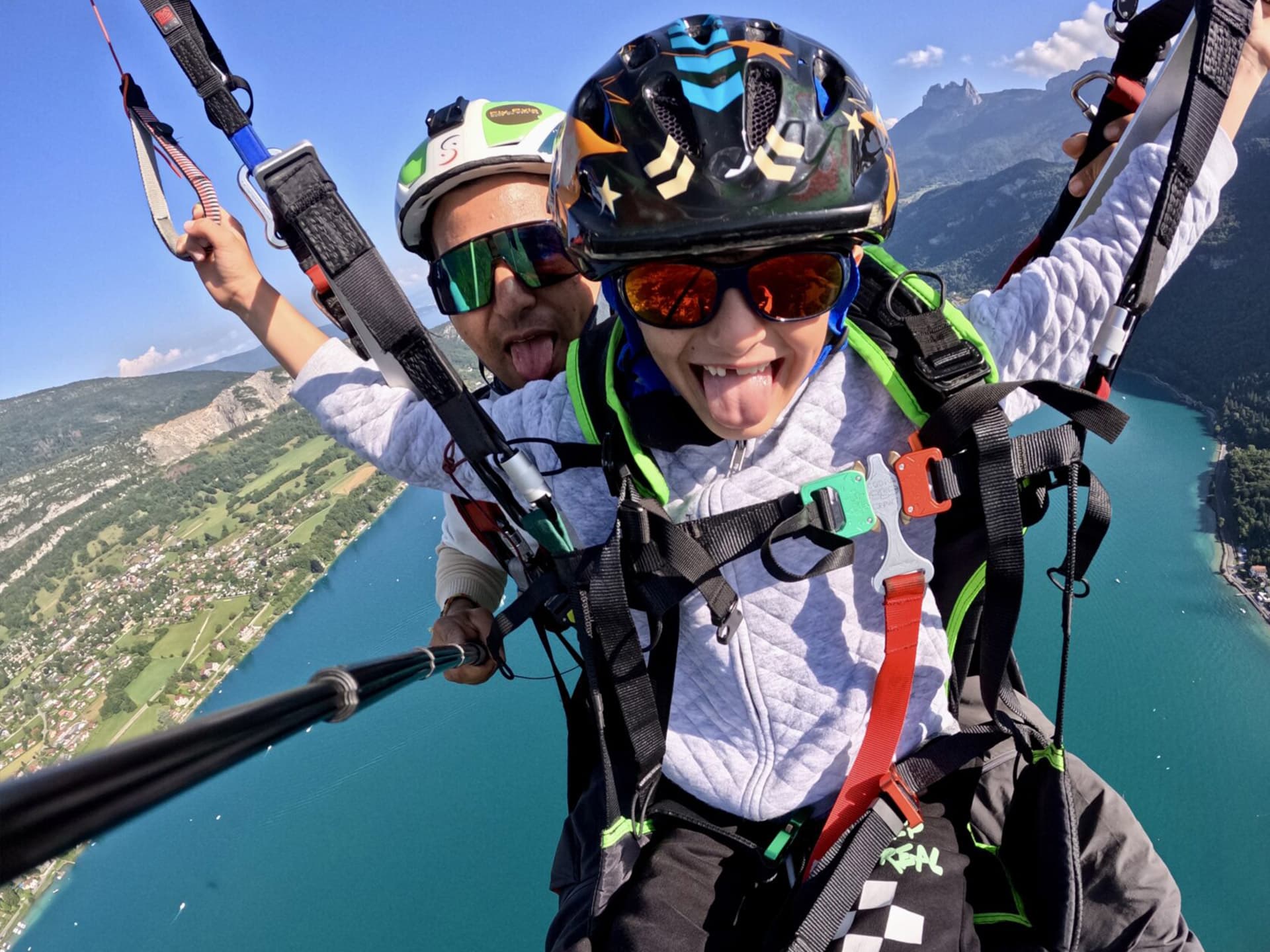 Enfant en parapente biplace survolant le lac d'Annecy avec un pilote diplômé.